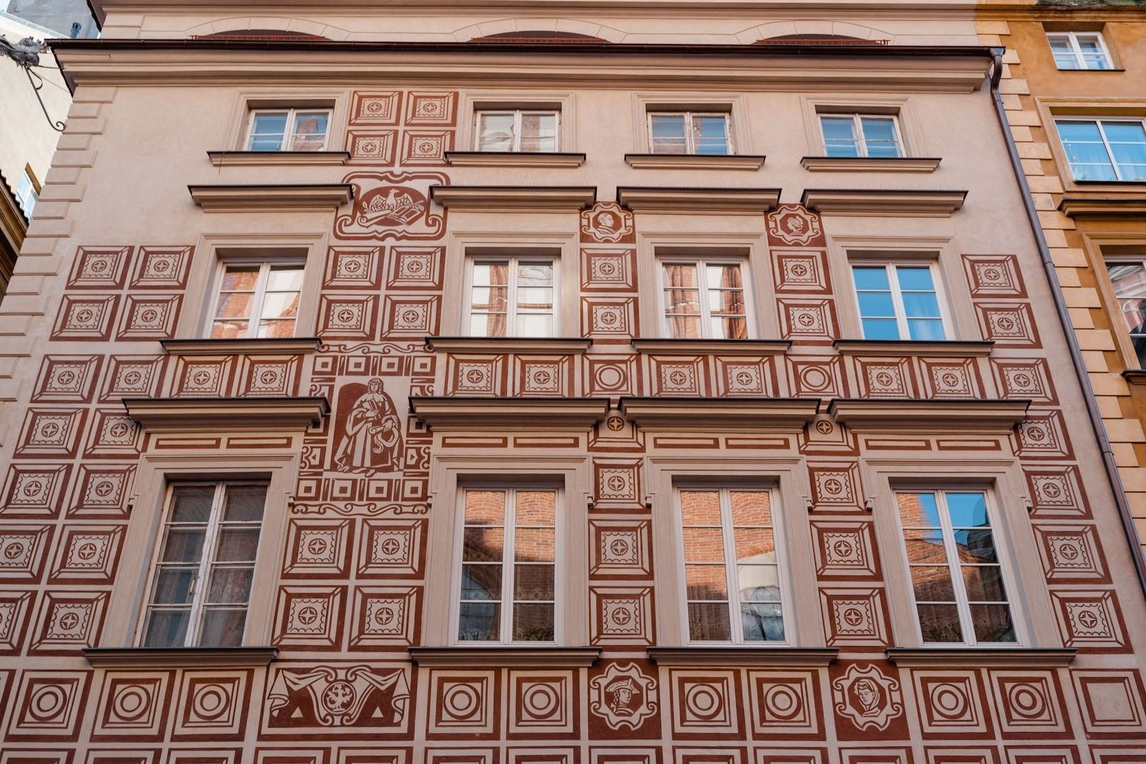 Ornate sgraffito facade with geometric patterns and figurative panels